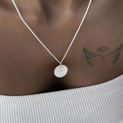 Silver necklace with a round pendant on a person's neck