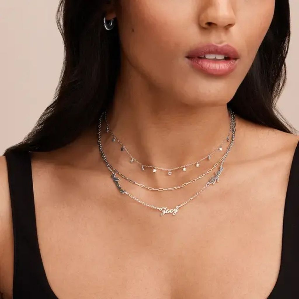 Close-up of a woman wearing multiple necklaces with a plain background