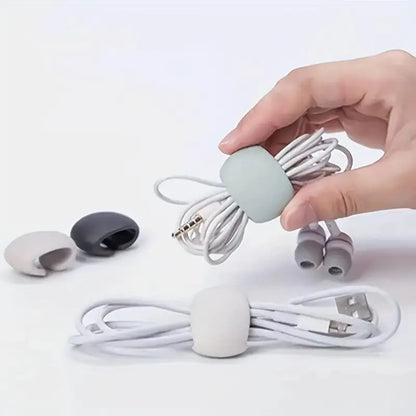 Hand holding a cable organizer with earbud accessories on a white background