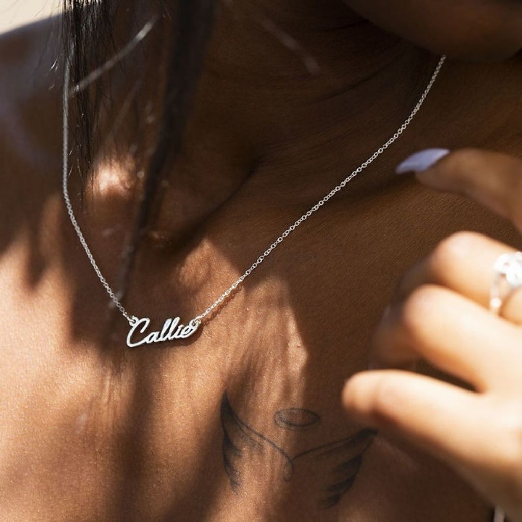 Person wearing a necklace with 'Callie' on it, close-up shot.
