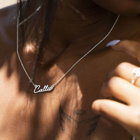 Person wearing a necklace with 'Callie' on it, close-up shot.