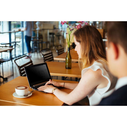 Woman using a laptop at a table in a cafe with a blurred background