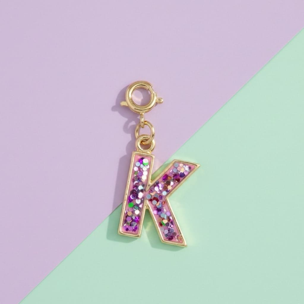 Glittery letter 'K' charm on a purple and green background