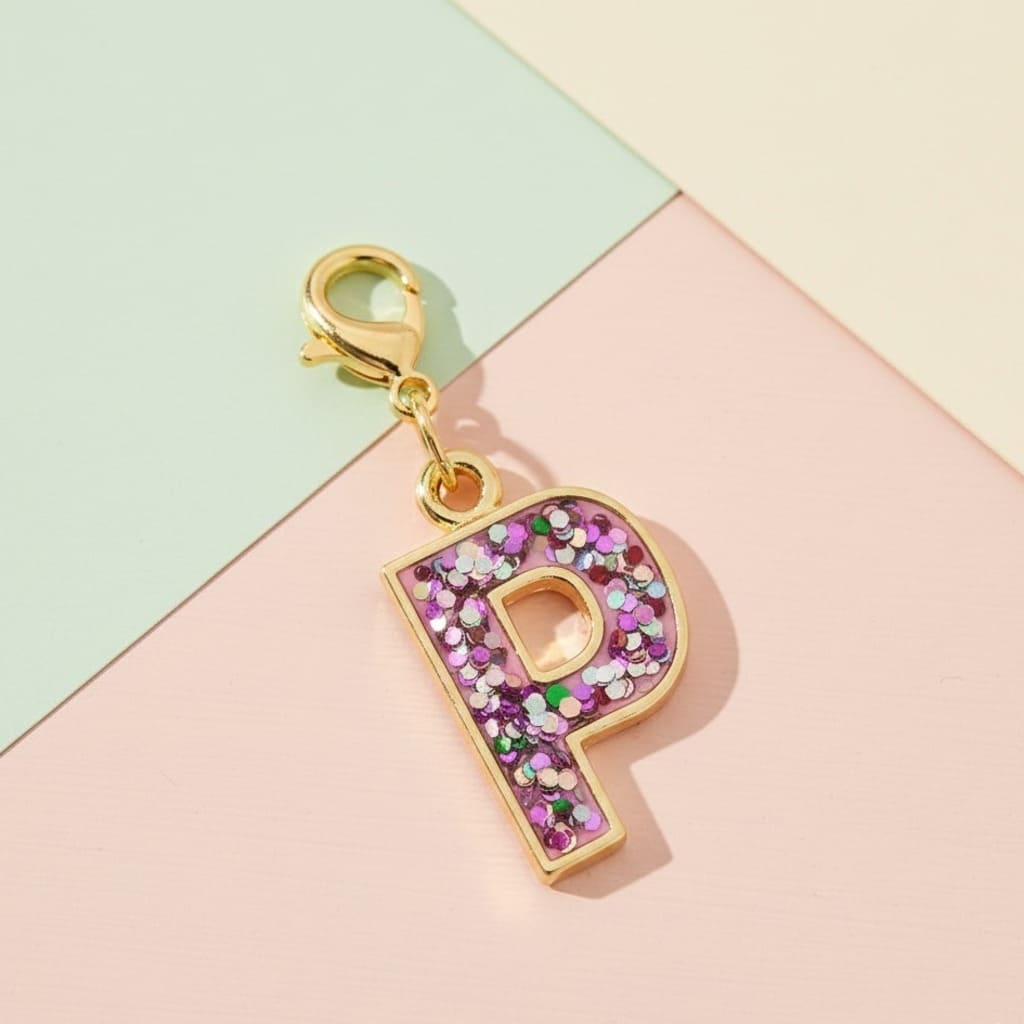 Gold charm with a purple letter 'P' on a colorful geometric background