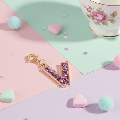 Decorative letter 'V' charm with glitter on a colorful background