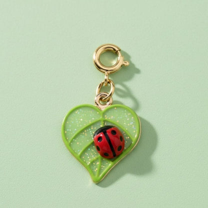 Green heart-shaped charm with a ladybug on a light green background