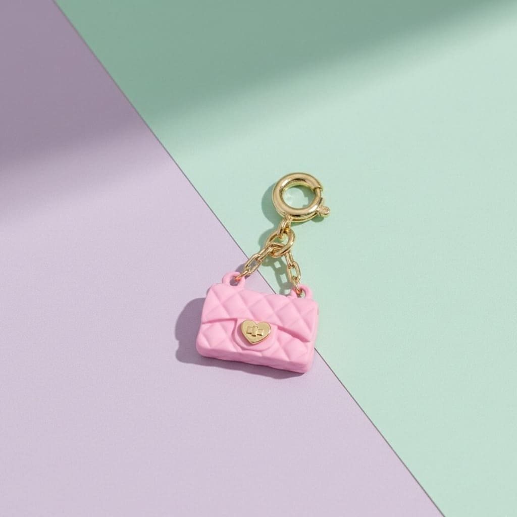 Pink purse charm with gold clasp on a pastel background