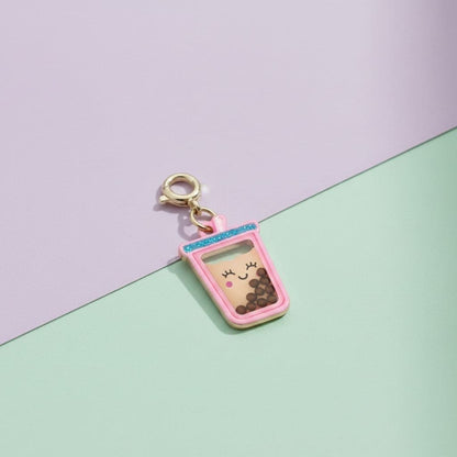 Pink coffee cup charm with a smiling face on a two-tone purple and green background