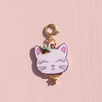 Cat-shaped keychain with gold accents on a pink background