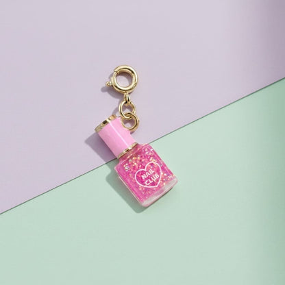 Pink nail polish charm with gold top on a pastel background
