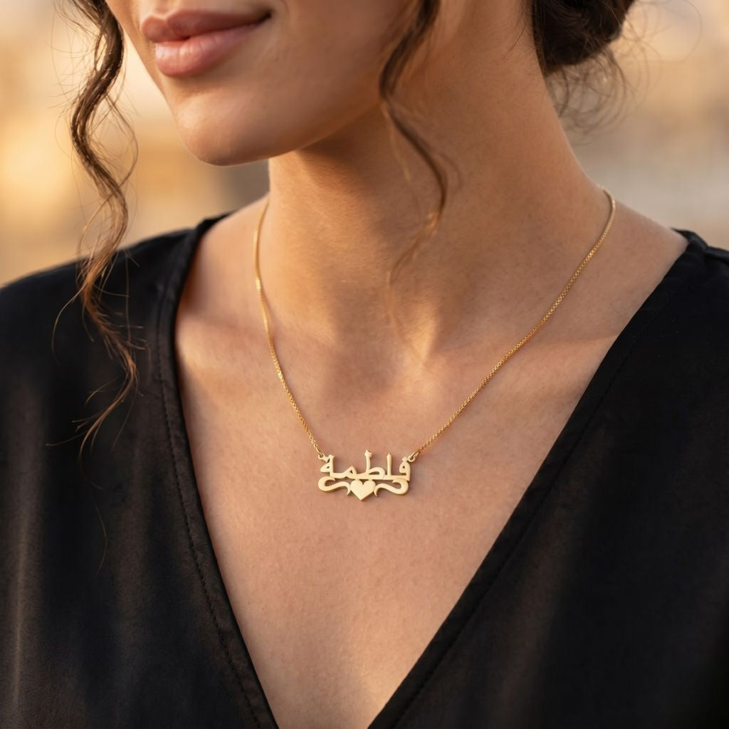 Gold necklace with an Arabic name pendant worn by a person against a blurred background