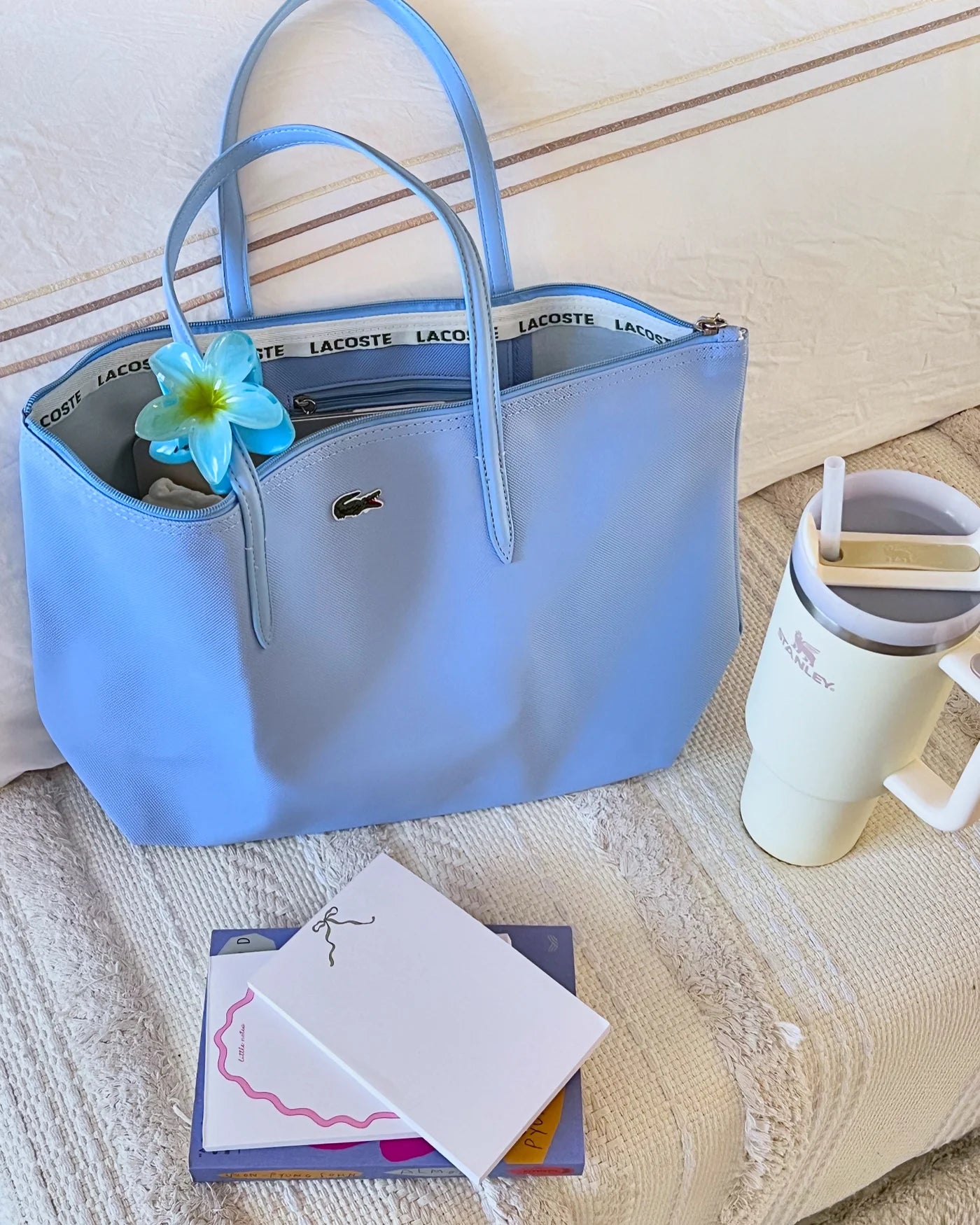 Blue handbag with floral detail on a textured surface next to a mug and cards