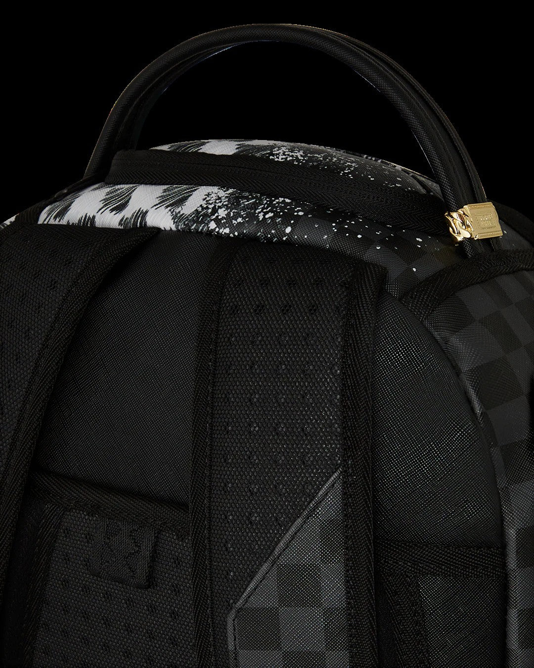 Close-up of a black backpack with floral patterned strap and gold zipper pull on a black background