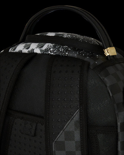 Close-up of a black backpack with floral patterned strap and gold zipper pull on a black background