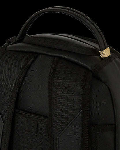 Close-up of a black backpack with a gold zipper pull on a black background