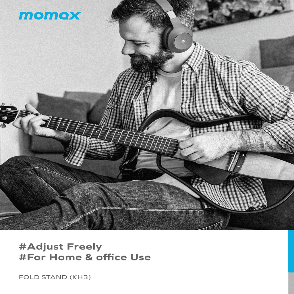 Man playing guitar with headphones on, sitting on a couch with 'momax' branding.