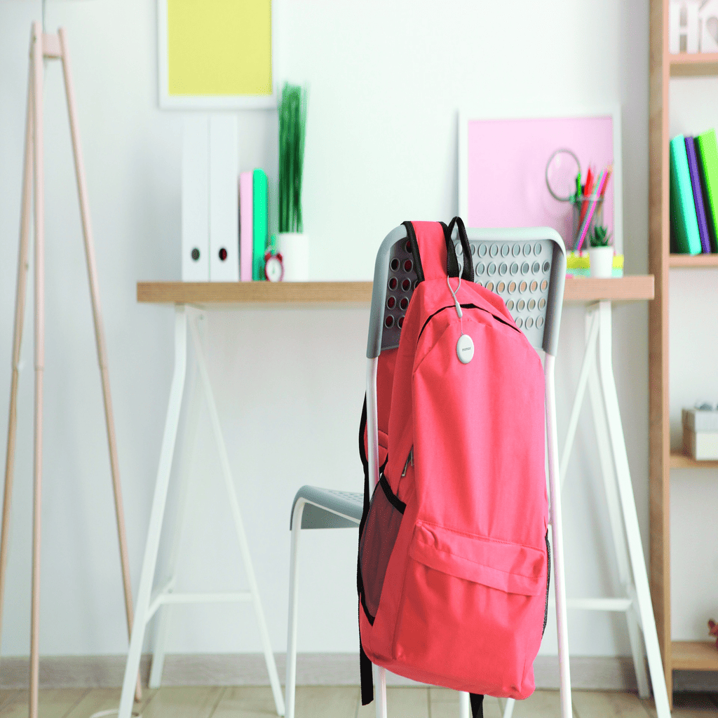 Pink backpack hanging on a chair in a room with shelves and decor.