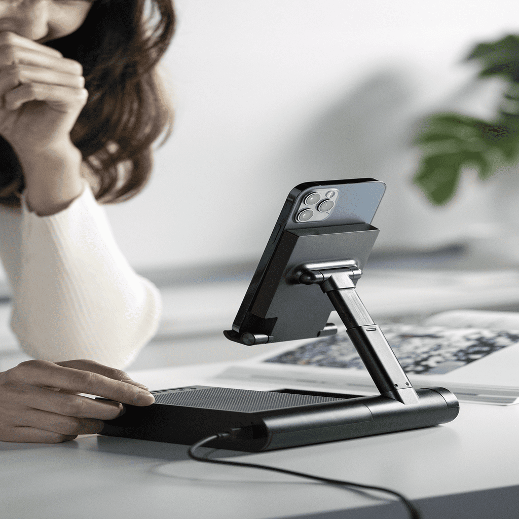 Person using a phone stand with a phone on a desk