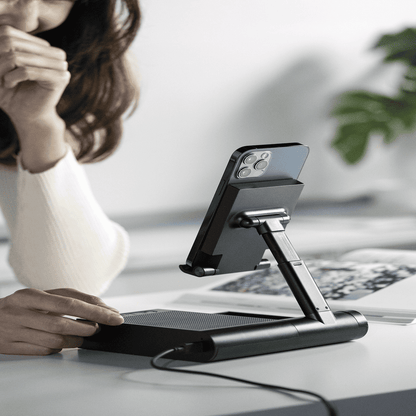 Person using a phone stand with a phone on a desk