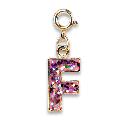 Gold charm with pink glittery letter 'F' on a white background