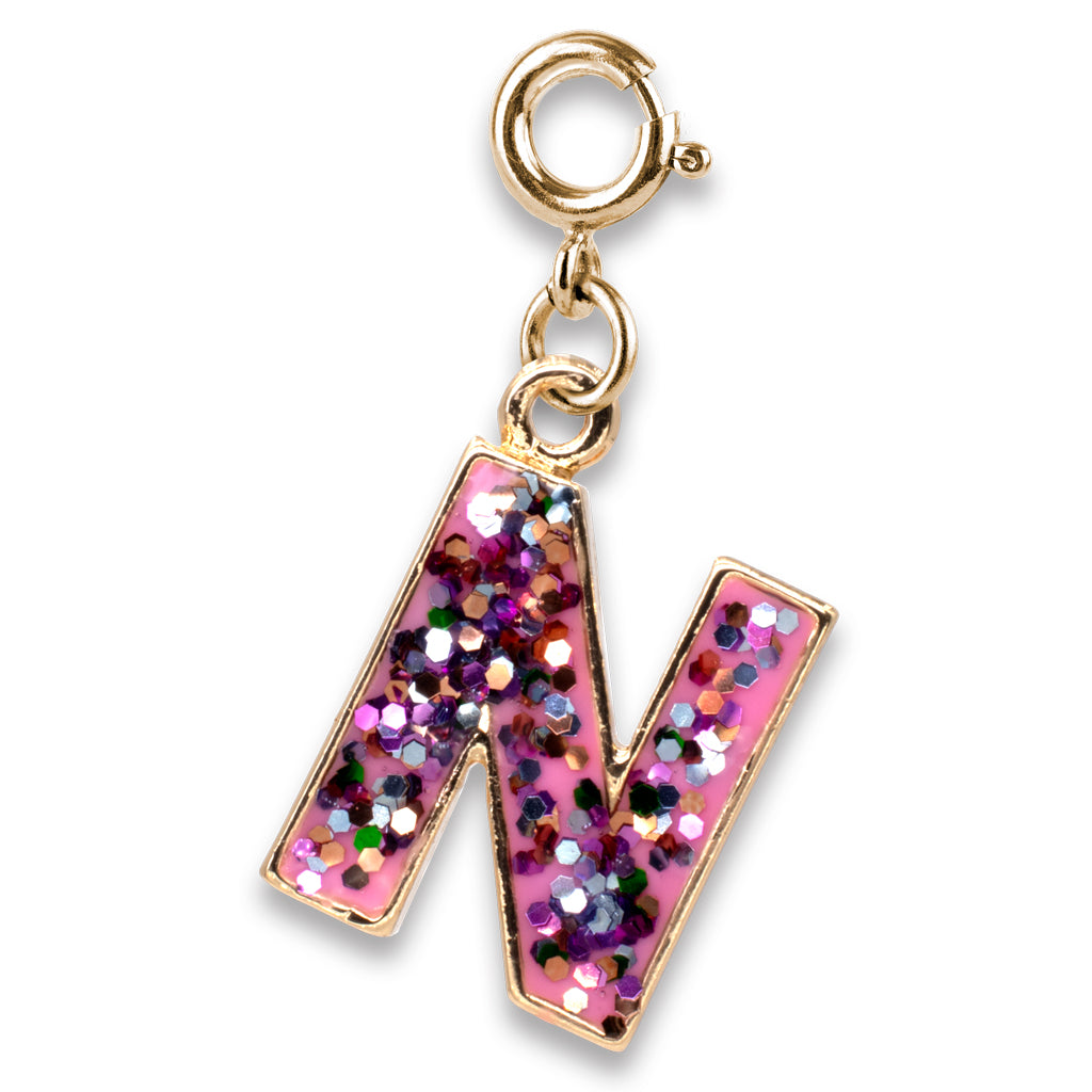 Gold charm with a pink letter 'N' filled with glitter on a white background
