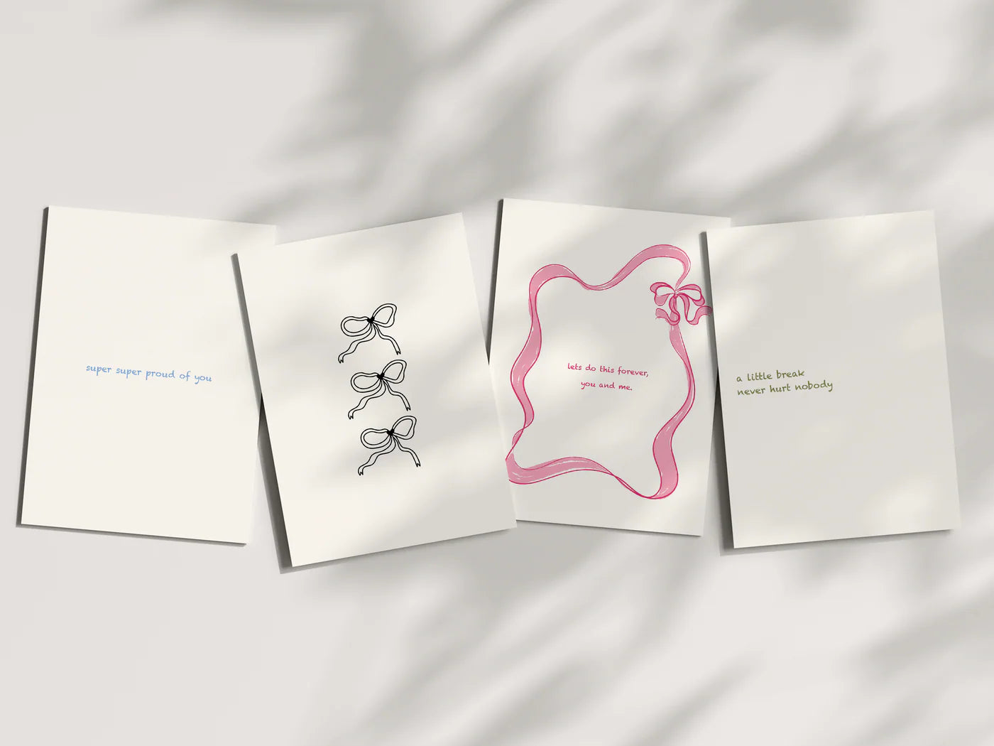 Four white greeting cards with decorative bows on a light gray background