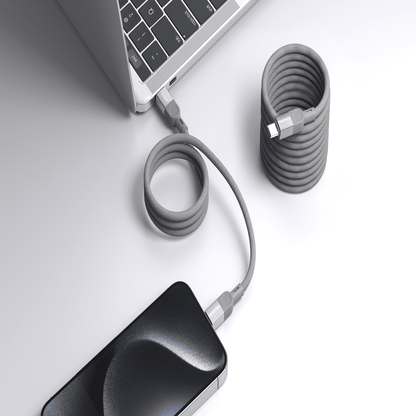 Laptop and phone with coiled cables on a light gray surface