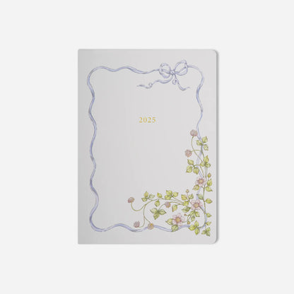 Decorative notebook with floral design and bow on a light gray background