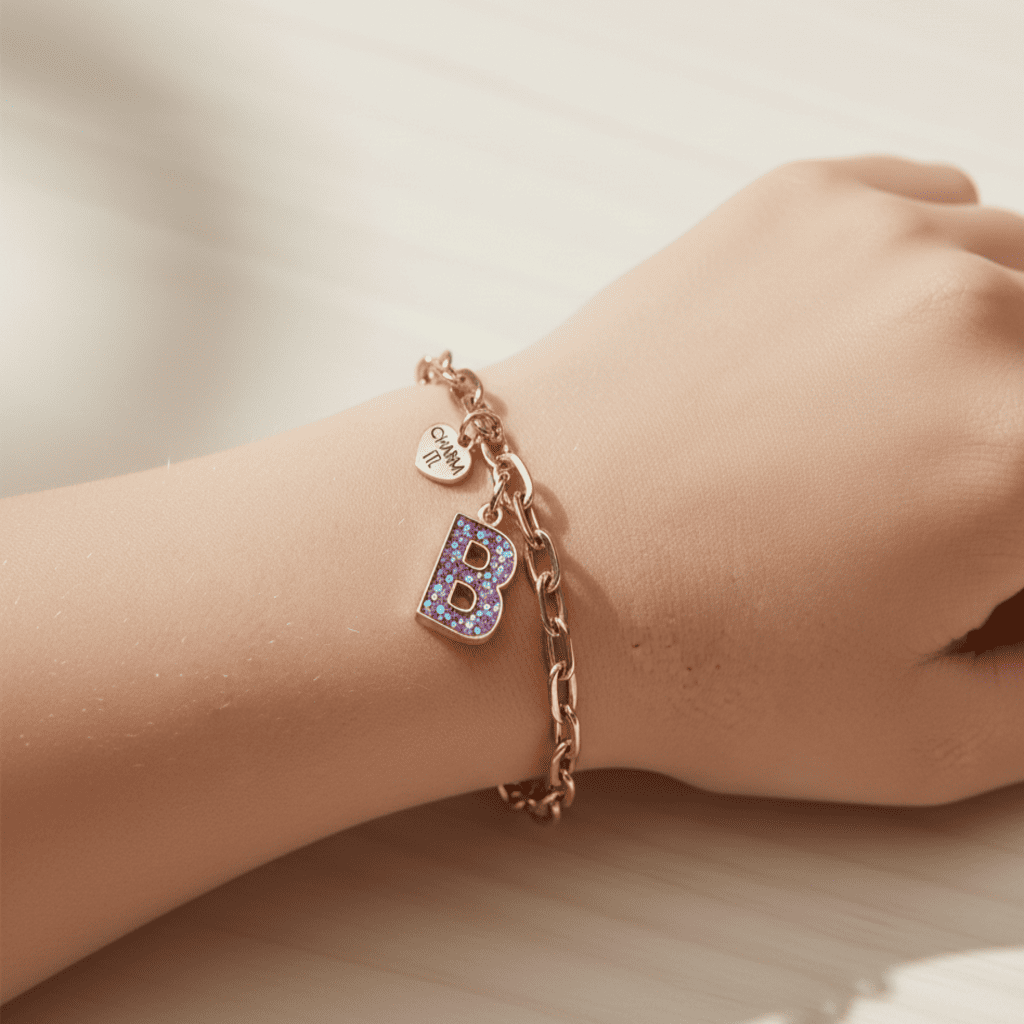 Rose gold bracelet with a letter 'B' charm on a wrist against a neutral background