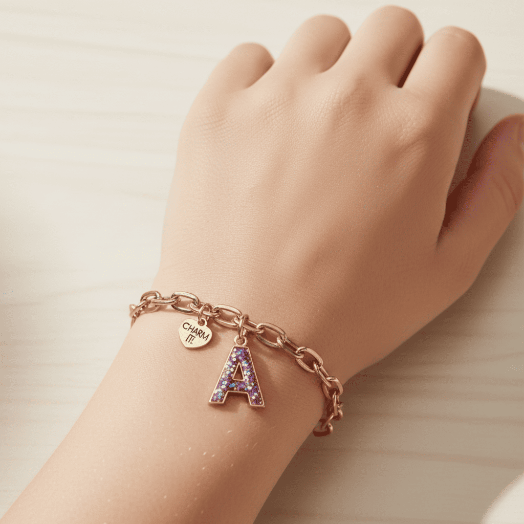Hand wearing a bracelet with letter 'A' charm on a neutral background