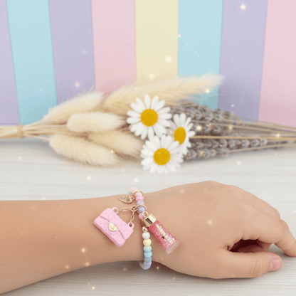 Hand wearing a colorful bracelet with charms against a pastel striped background