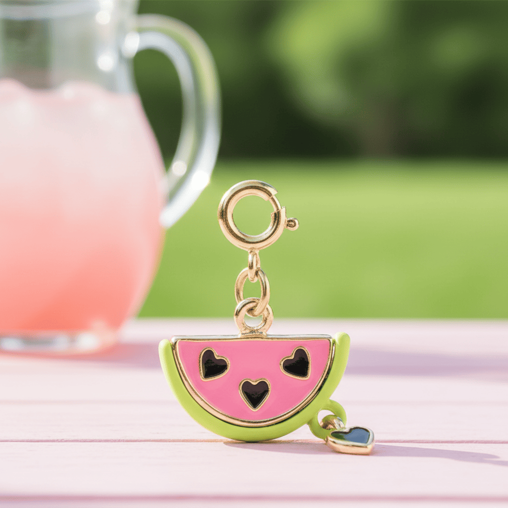 Watermelon-shaped keychain with black heart designs on a pink surface with a blurred background