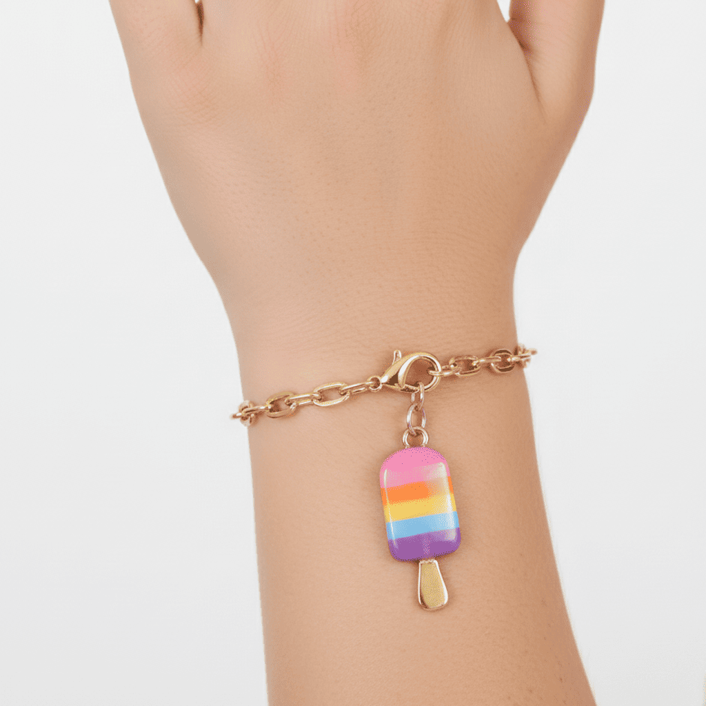 Bracelet with a rainbow popsicle charm on a wrist against a white background