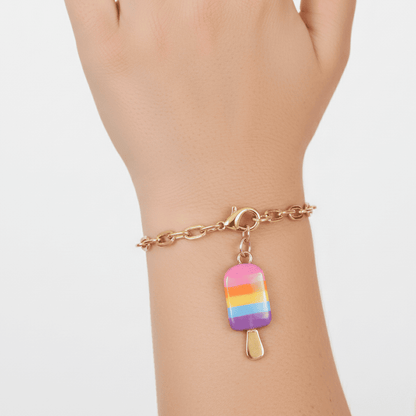 Bracelet with a rainbow popsicle charm on a wrist against a white background