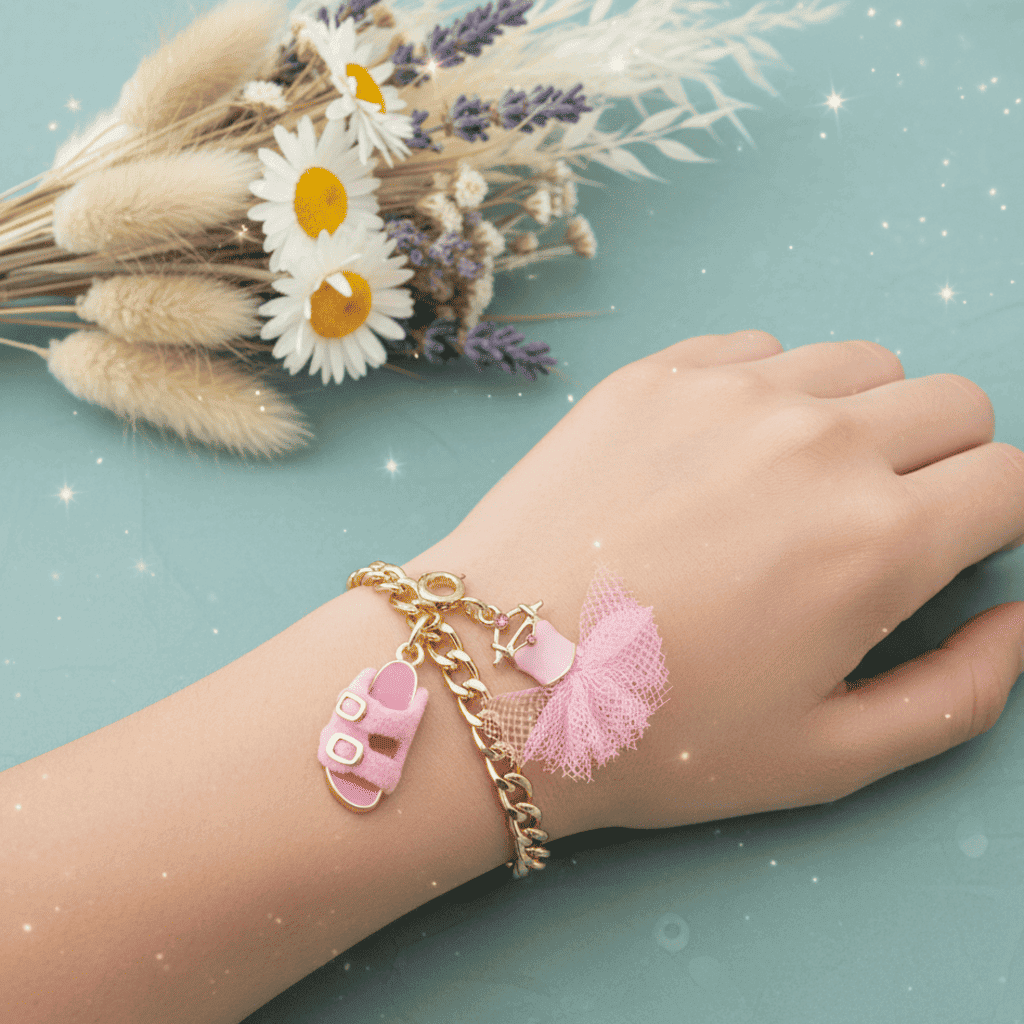 Hand wearing a gold bracelet with pink sandal charms on a light blue background with flowers.