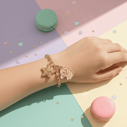 Hand wearing a gold bracelet with charms on a colorful background with macarons