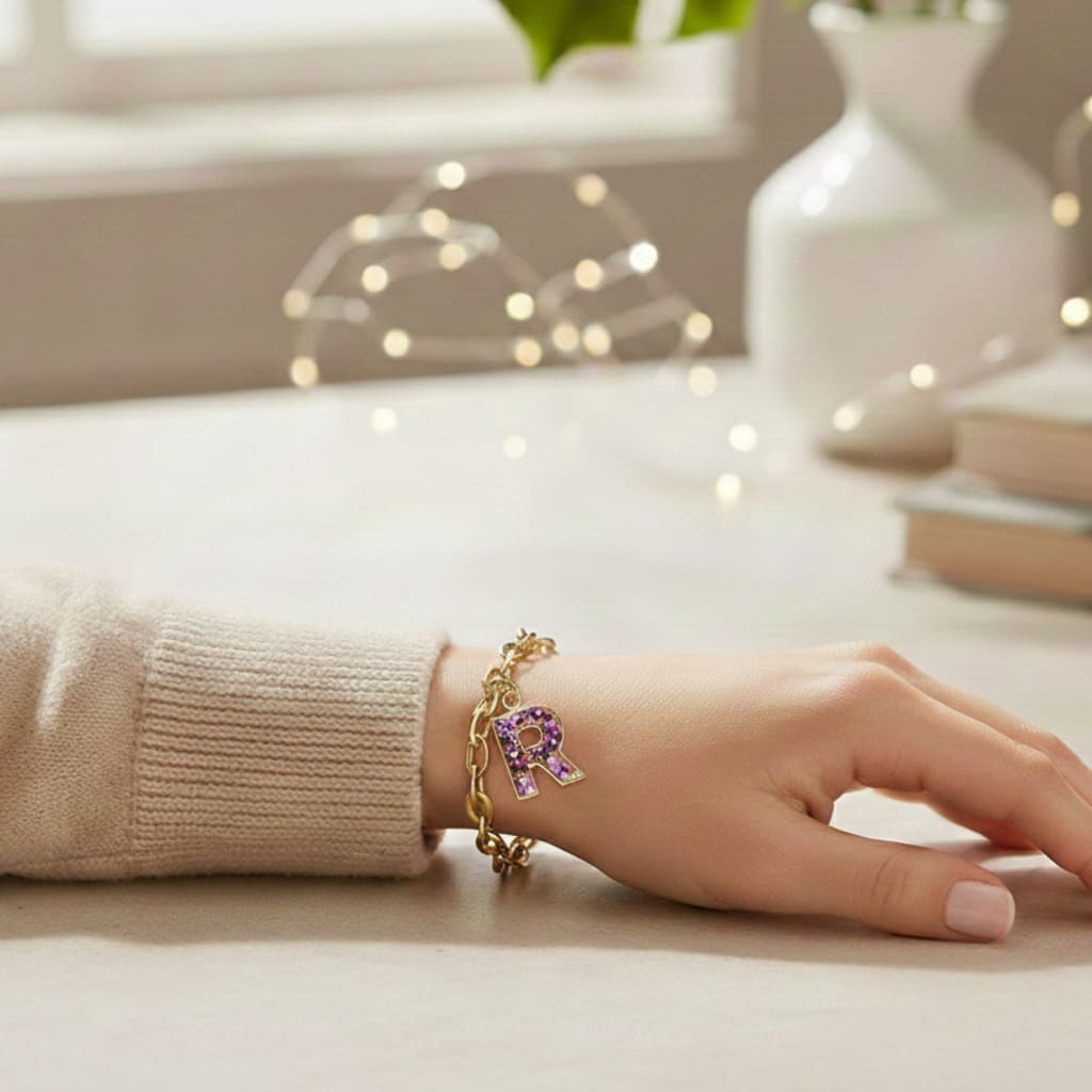 Hand wearing a bracelet with a purple charm on a light surface, with a blurred indoor background.
