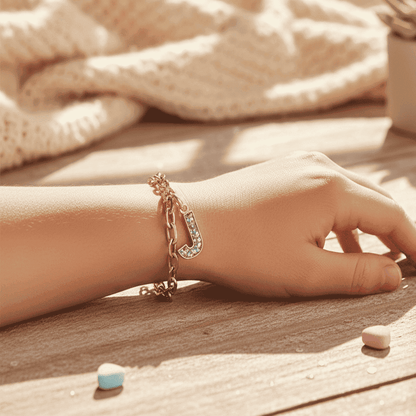 Hand wearing a gold bracelet on a wooden surface with light fabric in the background