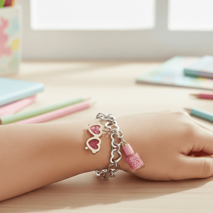 Child's hand wearing a bracelet with heart and nail polish bottle charms on a desk.