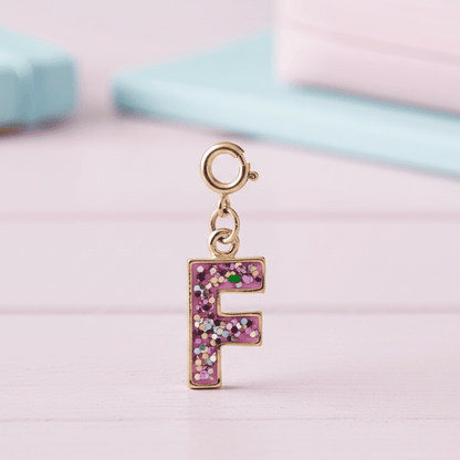 Letter 'F' charm with pink glitter on a pastel background