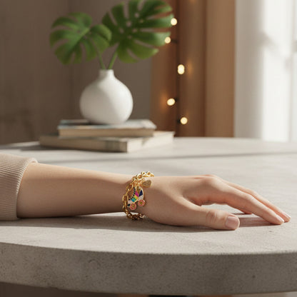 Hand wearing a gold bracelet with colorful beads on a neutral background