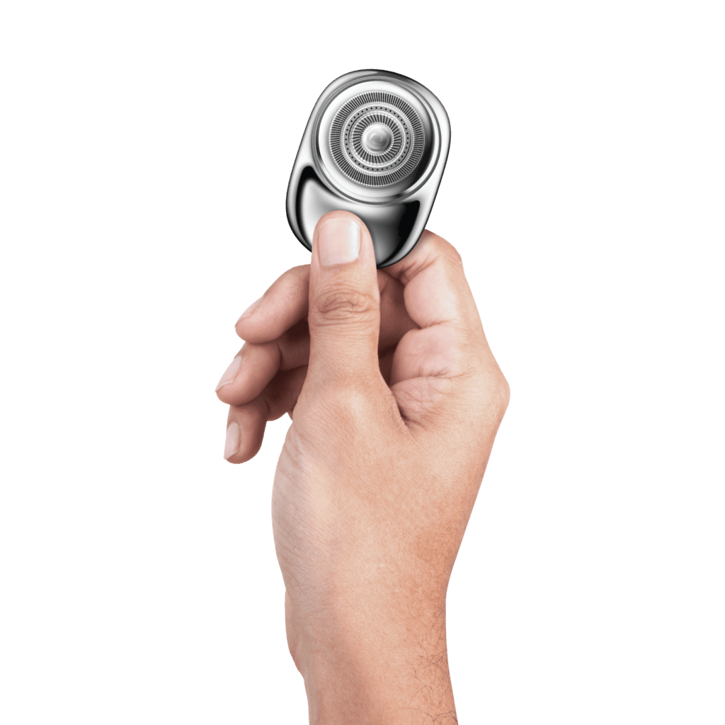 Hand holding a metallic shaver against a green background
