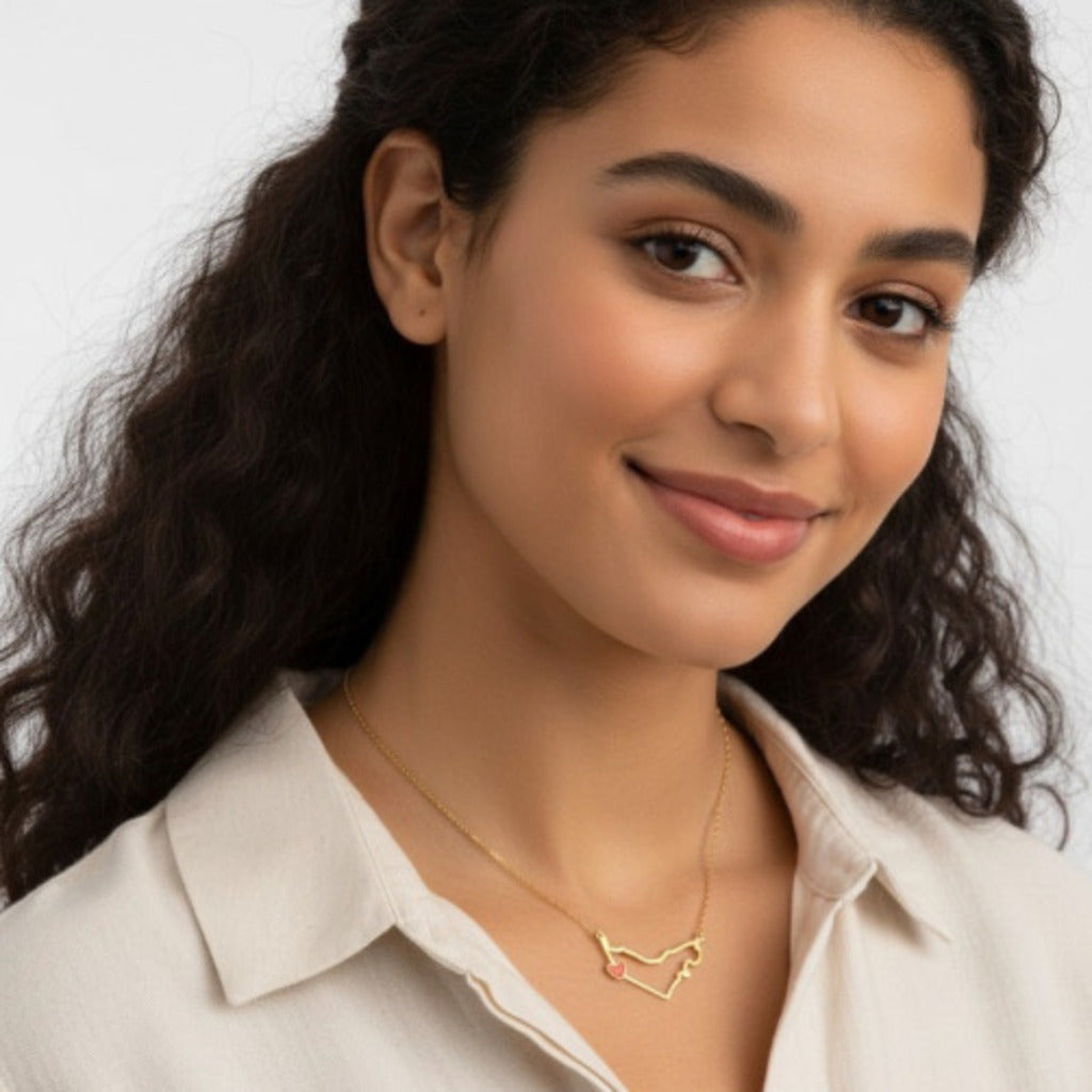 Woman wearing a gold necklace with a heart design on a plain background