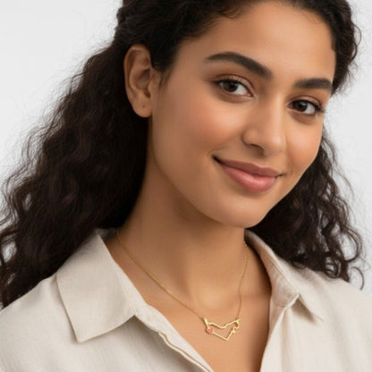Woman wearing a gold necklace with a heart design on a plain background