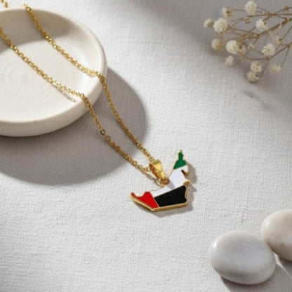Gold necklace with a flag pendant on a light surface with decorative elements