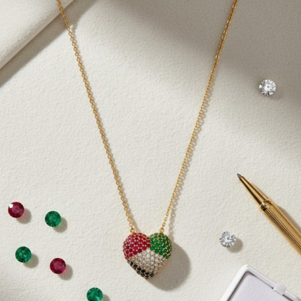 Heart-shaped necklace with colored stones on a light surface with gemstones and a pen.
