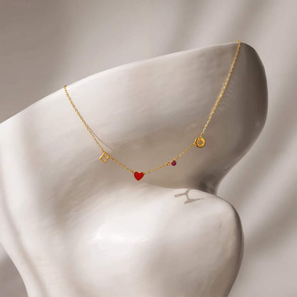 Gold necklace with heart and square charms on a mannequin bust against a neutral background