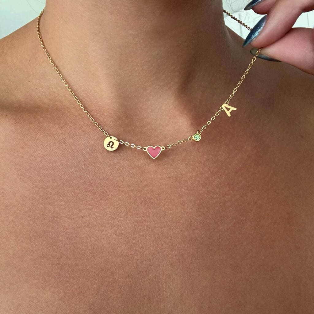 Gold necklace with heart and letter 'A' pendant on a person's neck