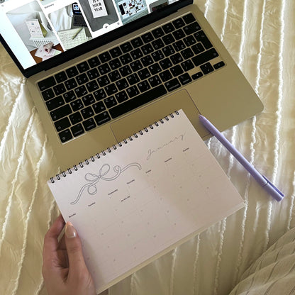 Laptop displaying a design on a screen with a notebook and pen on a textured surface