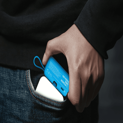 Hand holding a blue portable charger against a dark background